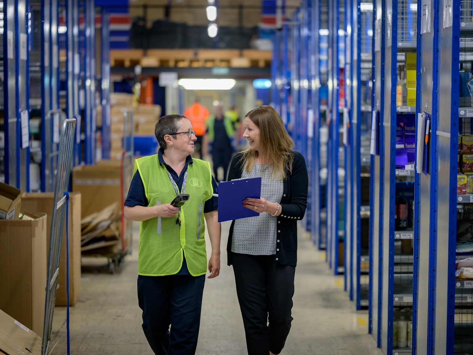 Two women walking down a warehouse aisle